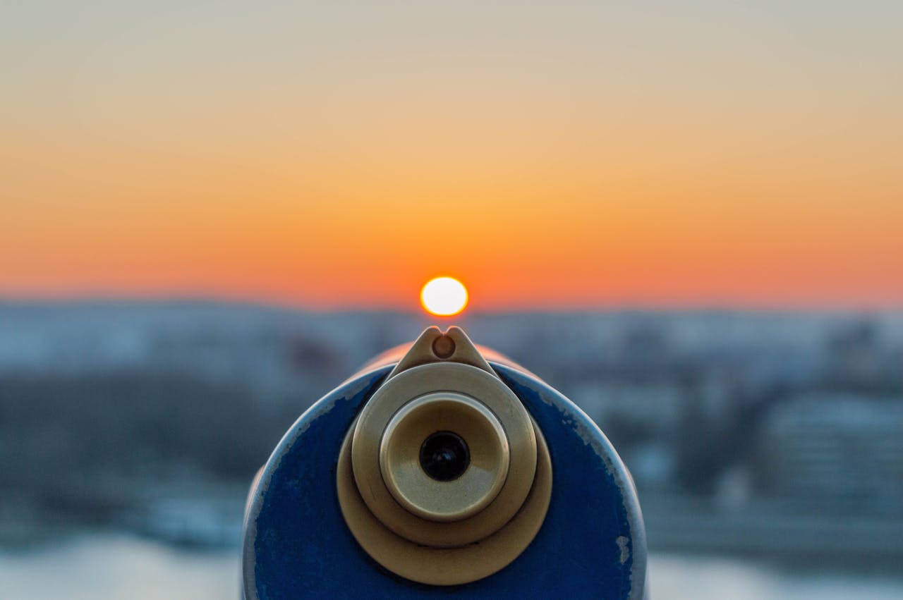 A stunning sunset with vibrant colors viewed through a telescope, creating a serene and contemplative scene.